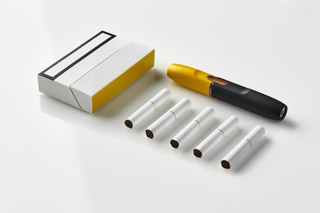 Cigarrillo electrónico negro y amarillo de nueva generación, un paquete y cinco barras de calor aisladas en blanco Nueva tecnología alternativa Sistema de calentamiento del tabaco Área de publicidad maqueta del espacio de trabajo Primer plano