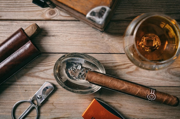 Cigarro cubano y una copa de brandy de coñac en la vista superior de fondo de madera