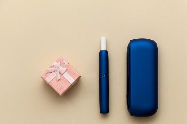 Cigarro eletrônico azul IQOS com caixa de presente em um fundo bege