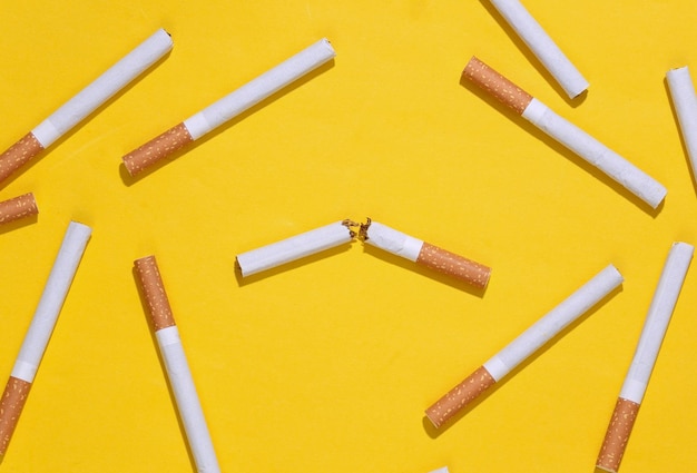 Cigarro quebrado em fundo amarelo brilhante. Parar de fumar