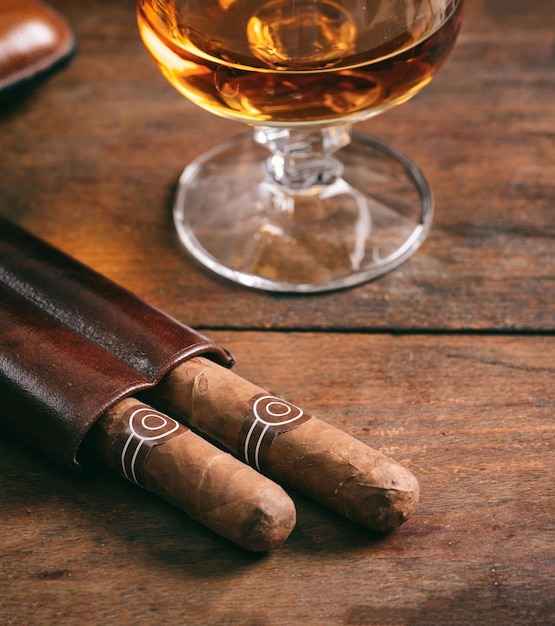 Los cigarros cubanos y el snifter con ron en la mesa de madera