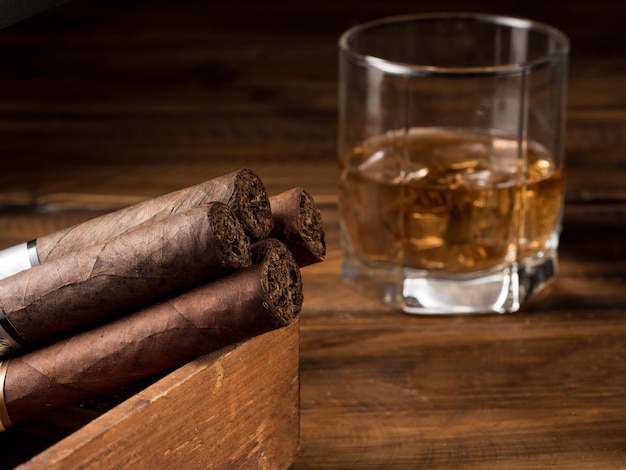 Cigarros y whisky en una mesa de madera Espacio de copia