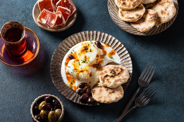 Cilbir ou ovos turcos mezze ovos escalfados cobertos com iogurte grego com ervas e depois regados com azeite de páprica picante quente Café da manhã turco tradicional com rahat