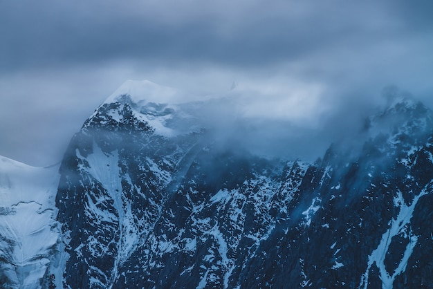 Cima de la montaña grande con nieve en el cielo nublado en el crepúsculo.