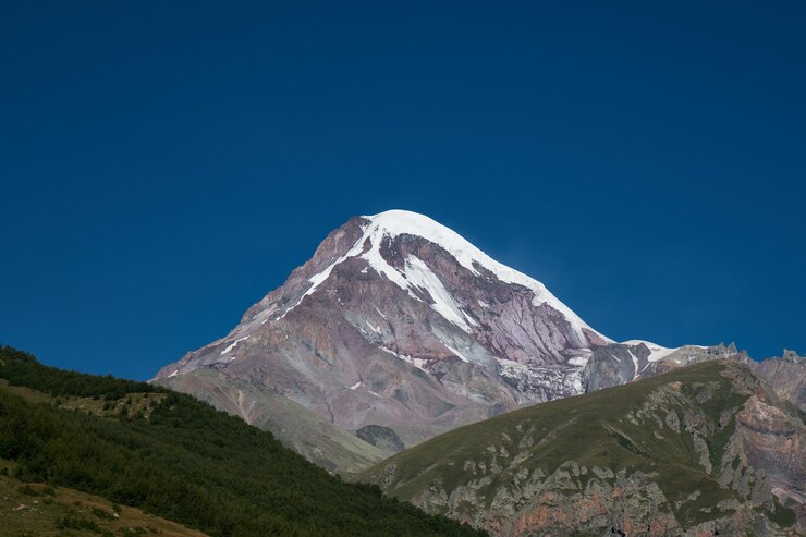 Foto la cima nevada del monte kazbek vista desde la cima en el pueblo de stepantsminda kazbegi