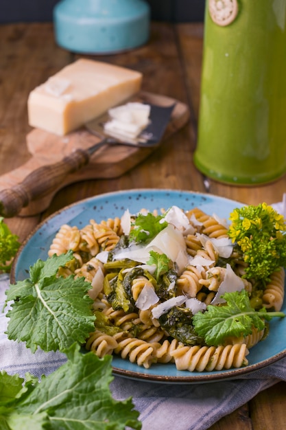 Cime di Rapa Nudeln in einem Teller mit Parmesan auf einem Holztisch. Traditionelles Essen aus Süditalien aus Apulien. Foto im rustikalen Stil. Speicherplatz kopieren