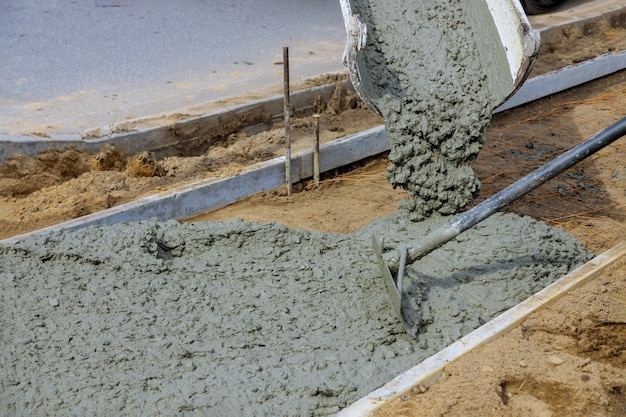 Cimento na frente da calçada de um novo prédio sob a superfície de concreto do trabalhador da construção civil na nova calçada