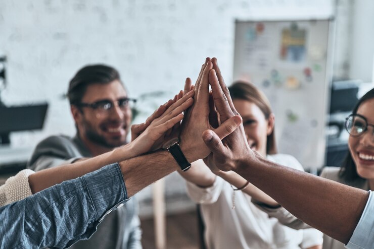 ¡Cinco altos! Vista superior de colegas de negocios dándose cinco en un símbolo de unidad y sonriendo mientras trabajan en la sala de juntas