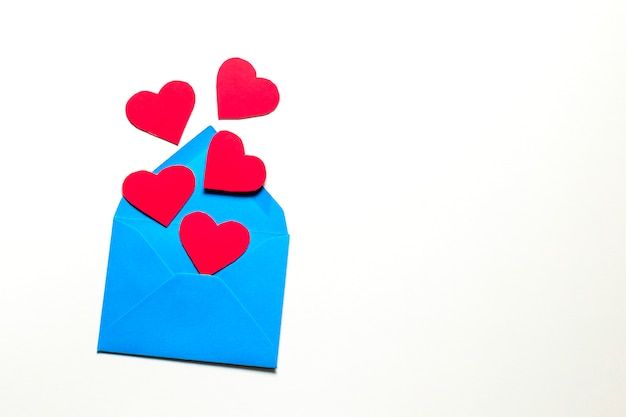 Cinco corazones rojos salen volando de un sobre de papel azul. Sobre un fondo claro. El concepto de celebración, amor y relaciones.