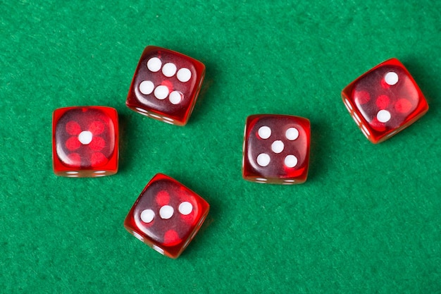 Cinco dadinhos vermelhos na mesa verde