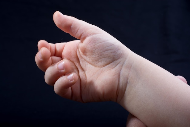 Cinco dedos de la mano de un niño en parte vistos en fondo negro