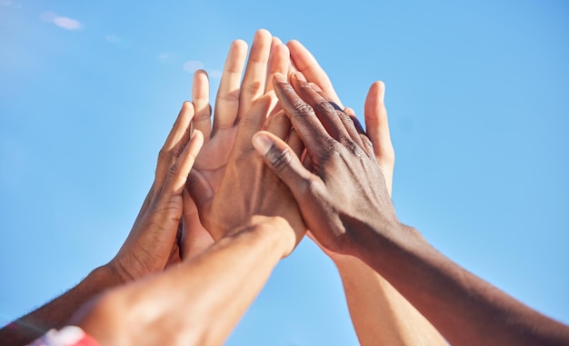 Cinco esportes e equipe com motivação de apoio e solidariedade durante um jogo com um céu azul Grupo de amigos de atletas ou homens com as mãos juntas para uma vitória, sucesso e parceria