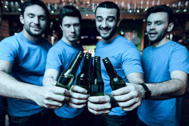 Foto cinco fanáticos del deporte bebiendo cerveza y celebrando.