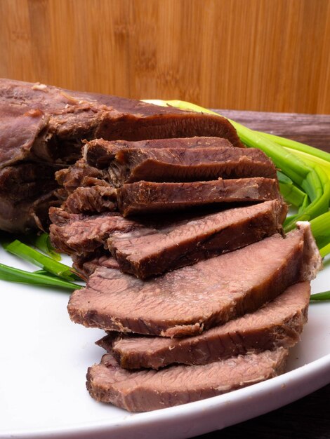 Cinco línguas cruas de carne de porco ou de boi com cebola verde sobre fundo de madeira, foco seletivo de concepção de comida gourmet