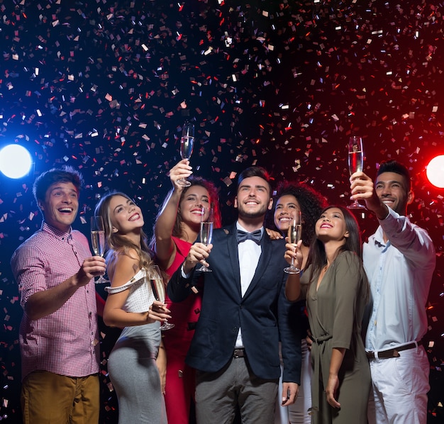 Cinco minutos para o ano novo. amigos felizes comemorando na boate com champanhe, olhando para cima, copie o espaço