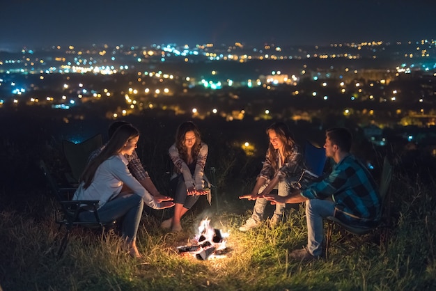 Las cinco personas descansan cerca de la hoguera. Noche