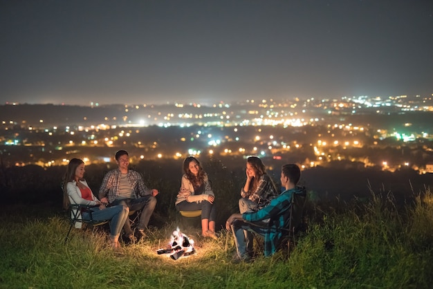 Las cinco personas se relajan cerca de la hoguera. Noche