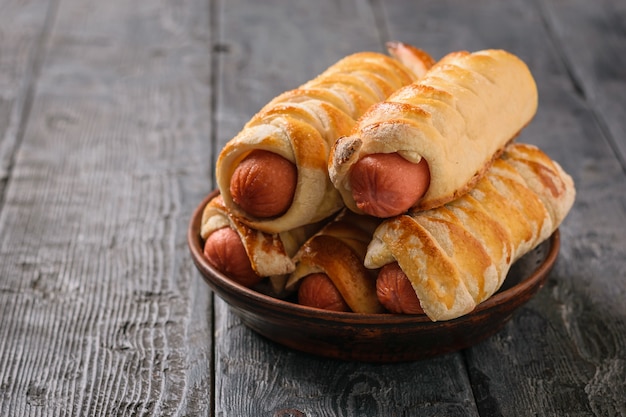 Cinco rolos de linguiça caseira em uma tigela de barro sobre uma mesa rústica.