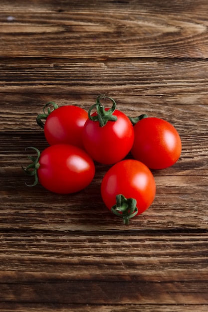 Cinco tomates cherry frescos en mesa de madera