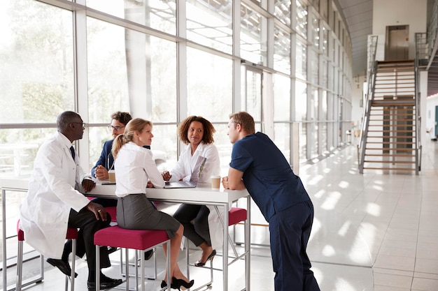 Cinco trabajadores de la salud en una mesa en el vestíbulo del hospital moderno