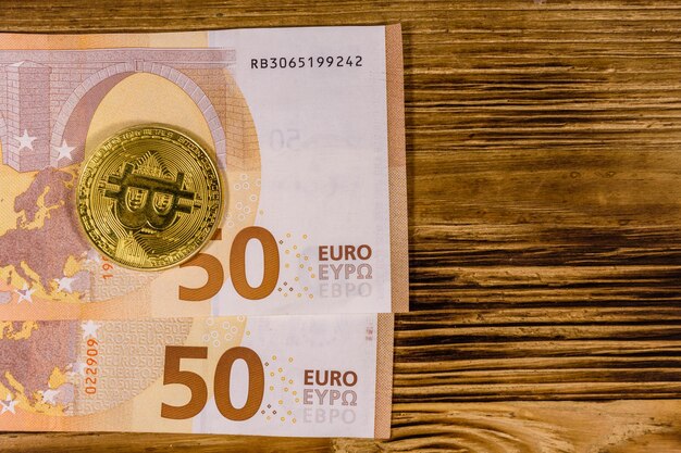 Cincuenta billetes en euros y bitcoins en el fondo de madera Vista superior