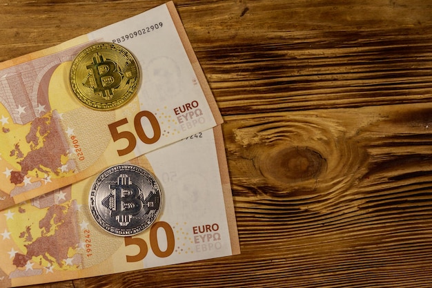 Cincuenta billetes en euros y bitcoins sobre fondo de madera Vista superior