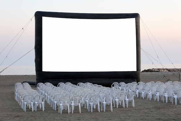Un cine al aire libre en la playa al atardecer con sillas sin gente
