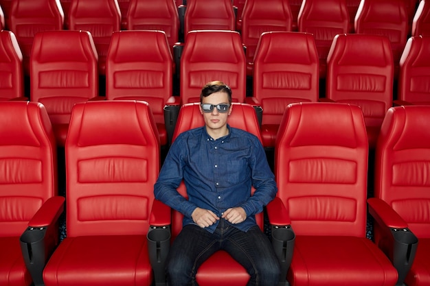 cine, tecnología, entretenimiento y concepto de personas - joven con gafas 3d viendo películas solo en un auditorio de teatro vacío