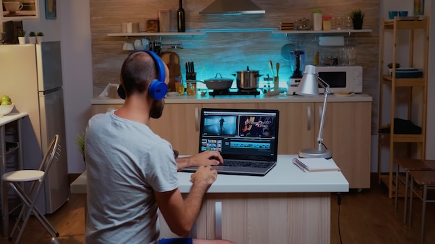 Foto cineasta criativo que edita vídeos em casa usando tecnologia moderna. criador de conteúdo homem em casa trabalhando na montagem de filme em um novo software para edição tarde da noite.