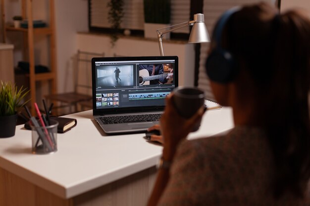 Foto cineasta editando secuencias de vídeo durante la noche en la cocina de casa