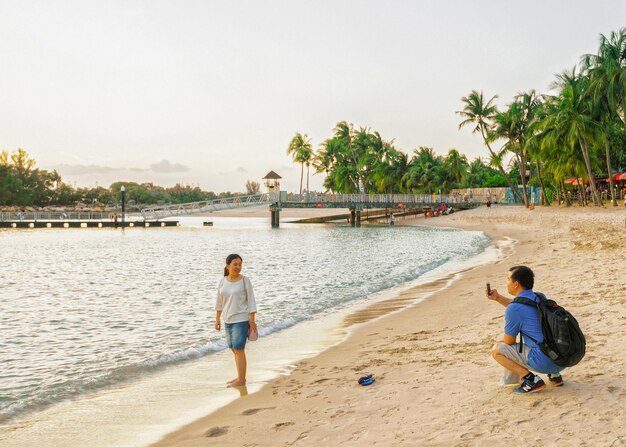 Cingapura, Cingapura - 1º de março de 2016: Pares tirando fotos na praia de Siloso, no resort da ilha de Sentosa, em Cingapura. É uma praia artificial com areia retirada da Malásia e da Indonésia.