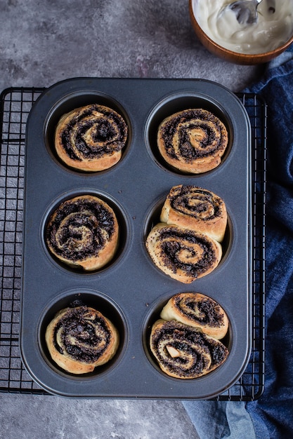 Cinnabon-Rolle mit Mohn auf Hintergrund. Selbst gemachtes Zimtbrötchen. Draufsicht