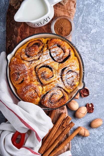 Cinnabon Zimtschnecken Brötchen mit Kürbis, Nuss, Karamell und Zuckercreme gefroren. Ansicht von oben. Süßes hausgemachtes Gebäck Weihnachtsbacken. Nahansicht. Kanelbule - schwedisches Dessert.