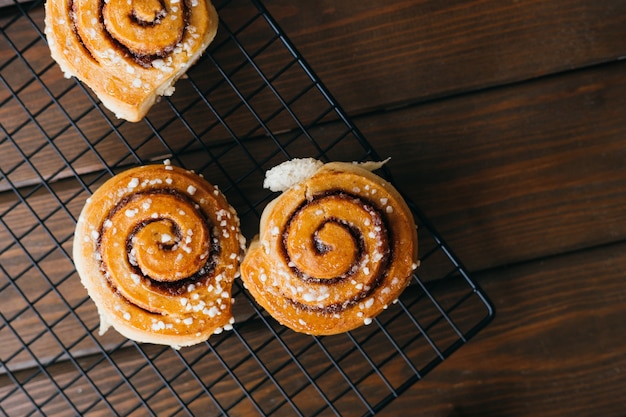 Cinnabons ganó una rejilla de alambre en la mesa. Concepto de comida. Pasteles dulces caseros sobre un fondo de madera. Vista superior