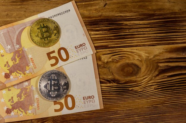 Cinquenta notas de euro e bitcoins na vista superior de fundo de madeira