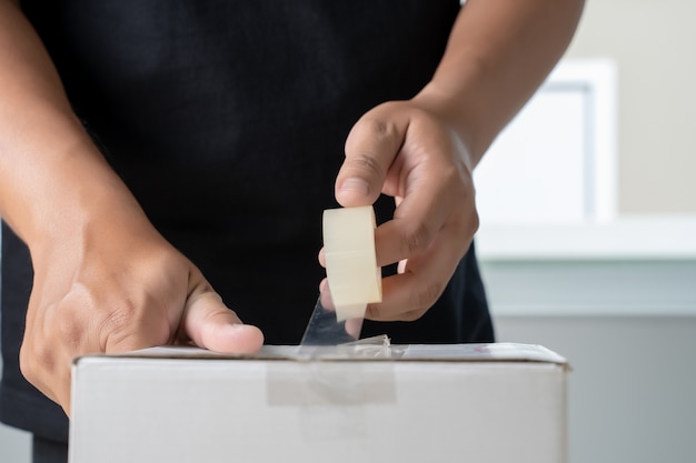 Cinta adhesiva de la caja de embalaje del hombre transparente de la mano del hombre.