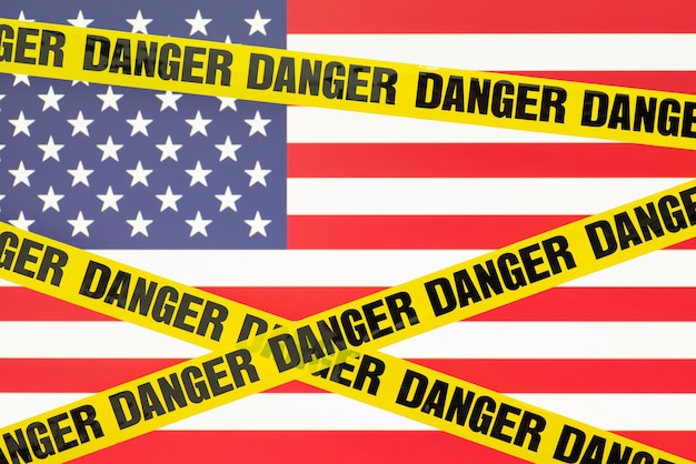 Cinta amarilla de peligro con bandera de Estados Unidos en el fondo