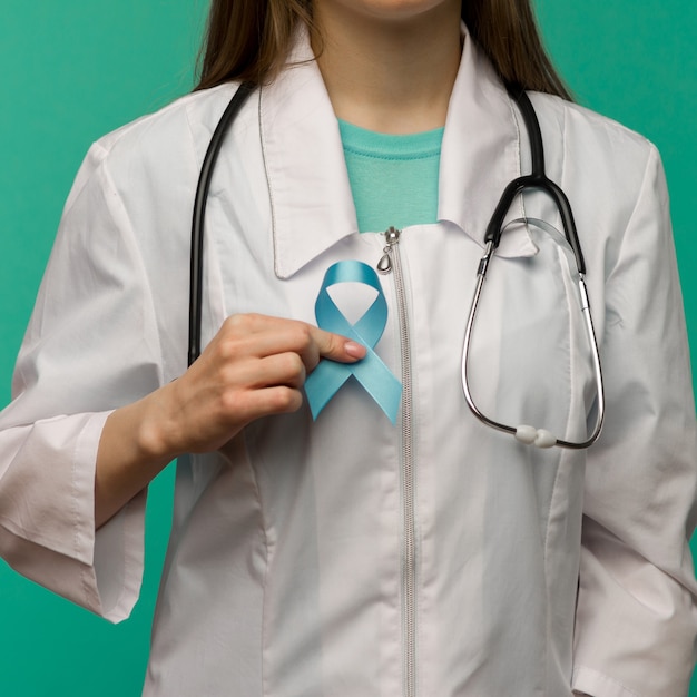 Cinta azul para la campaña de concientización sobre el cáncer de próstata y el concepto de atención médica de los hombres con un lazo simbólico en la mano del médico