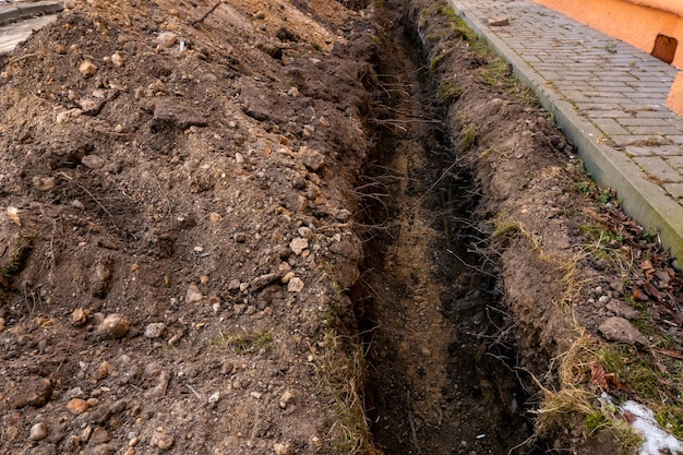 La cinta de barrera roja y blanca protege un lugar de peligro La cinta de advertencia indica el peligro de estar en el territorio del sitio de construcción Trincheras excavadas para colocar nuevas tuberías