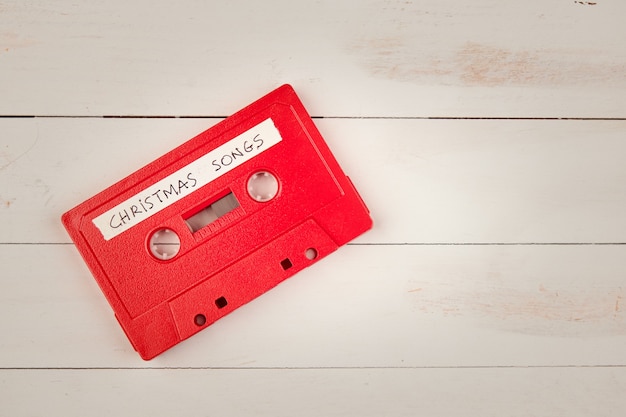 Cinta de cassette de audio con canciones navideñas sobre una mesa de madera blanca