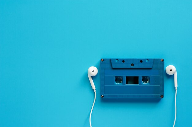 Cinta de cassette retra con los auriculares en el fondo azul para el concepto de la música y de la relajación