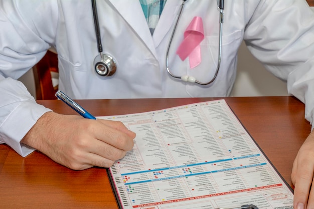 Cinta de conciencia rosa contra el médico que toma notas en el expediente de un paciente