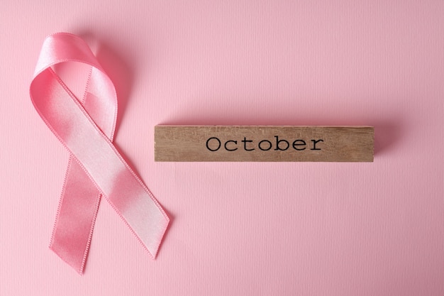 Cinta de concienciación sobre el cáncer de mama y bloque de madera con texto octubre sobre fondo rosa