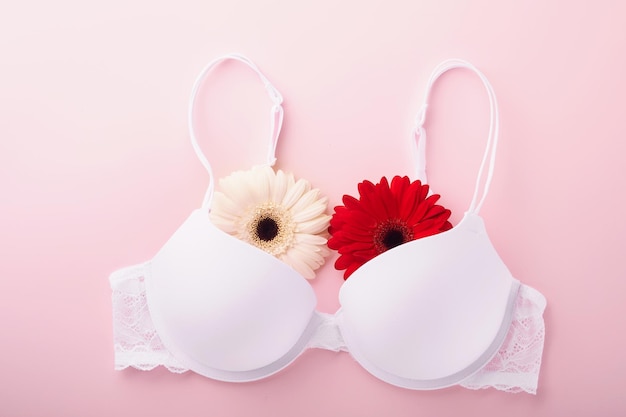 Cinta de concientización sobre el cáncer de mama Gerberas de sostén blanco y rojo con cinta de cinta rosa sobre un sostén femenino sobre fondos Concienciación sobre el cáncer de mama y Día mundial del cáncer de octubre Día rosa Vista superior Mock up