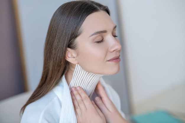 Foto cinta de cuello. linda joven visitando un centro de belleza y con un procedimiento de grabación en el músculo del cuello