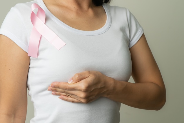 Cinta insignia rosa en el pecho de la mujer para apoyar la causa del cáncer de mama. concepto de concientización sobre el cáncer de mama
