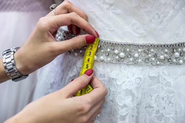 Cinta métrica amarilla con manos femeninas y vestido de novia