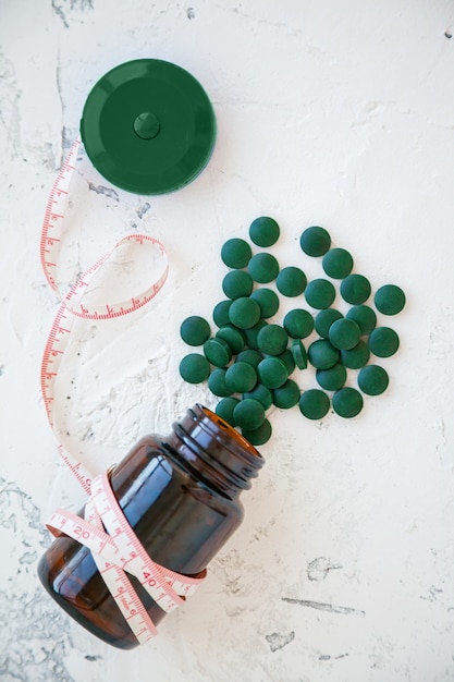 Cinta métrica con una botella de pastillas de espirulina verde