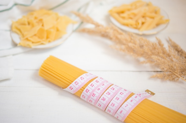 Foto cinta métrica con un montón de pasta italiana sin cocer, espagueti, variedades de pasta. dieta, concepto de comida saludable