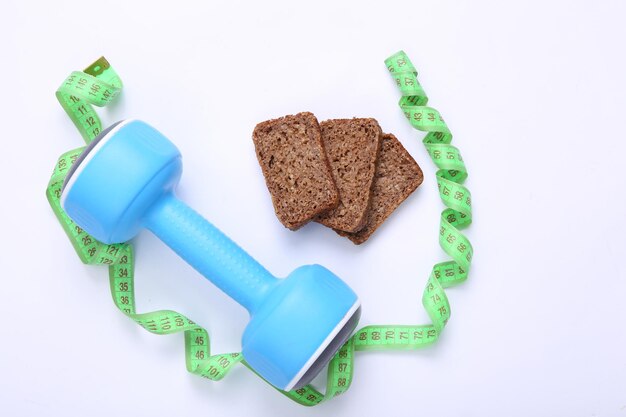 Foto cinta métrica y pesas dieta pan de centeno de grano entero sobre un fondo blanco concepto de fitness de dieta de pérdida de peso